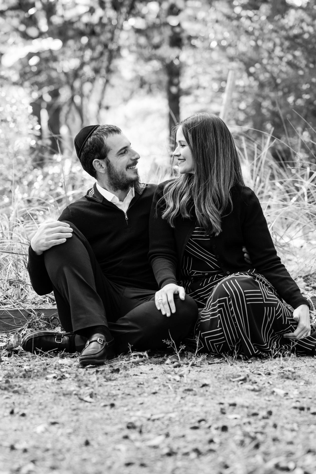 Black-and-white portrait of parents sitting together on a woodland path