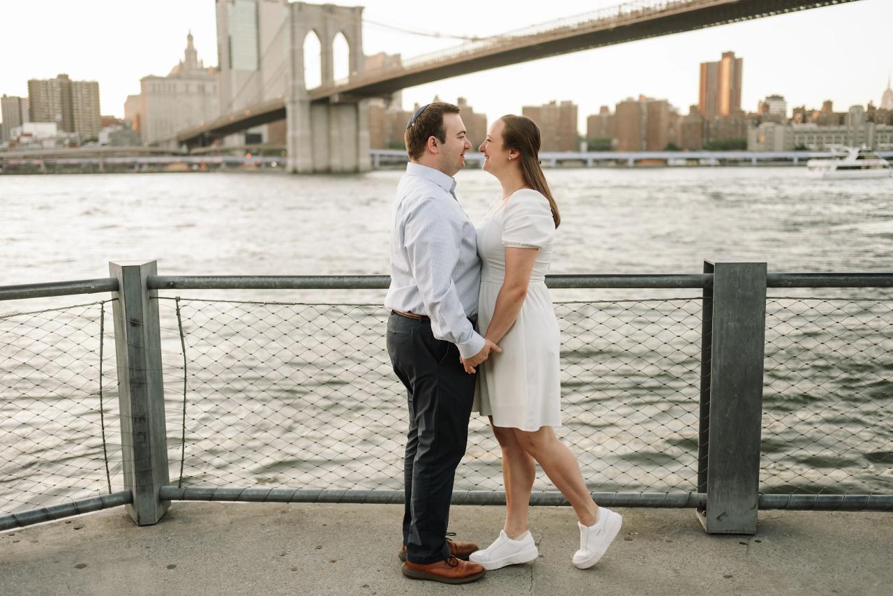 Couple standing together beside the Brooklyn Bridge at golden hour