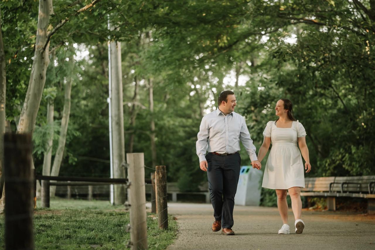 Couple walking together beneath tall trees