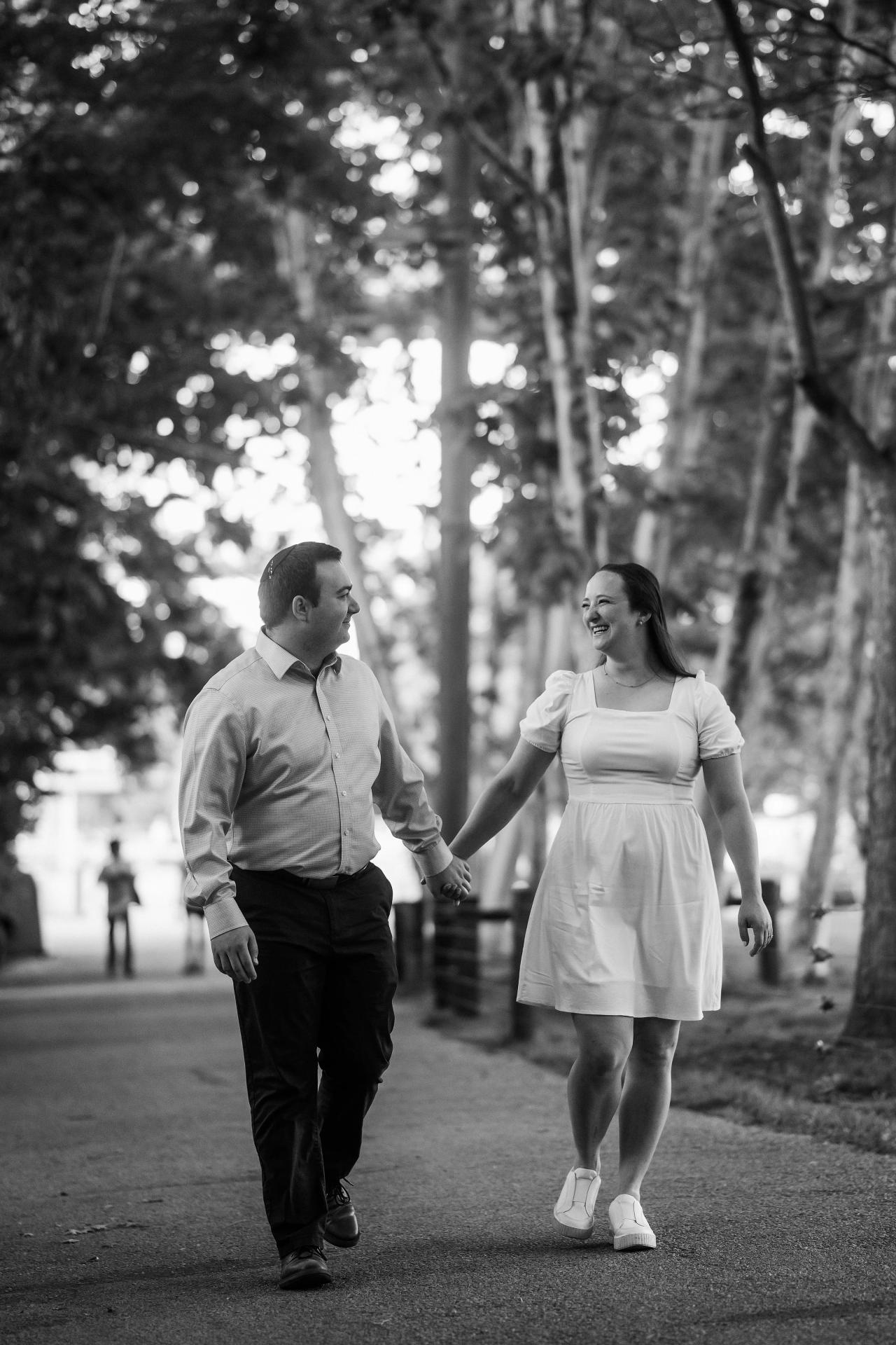 Black-and-white portrait of a couple holding hands on a park path