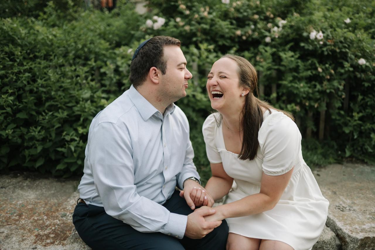 Couple laughing while sitting together on a garden stone bench