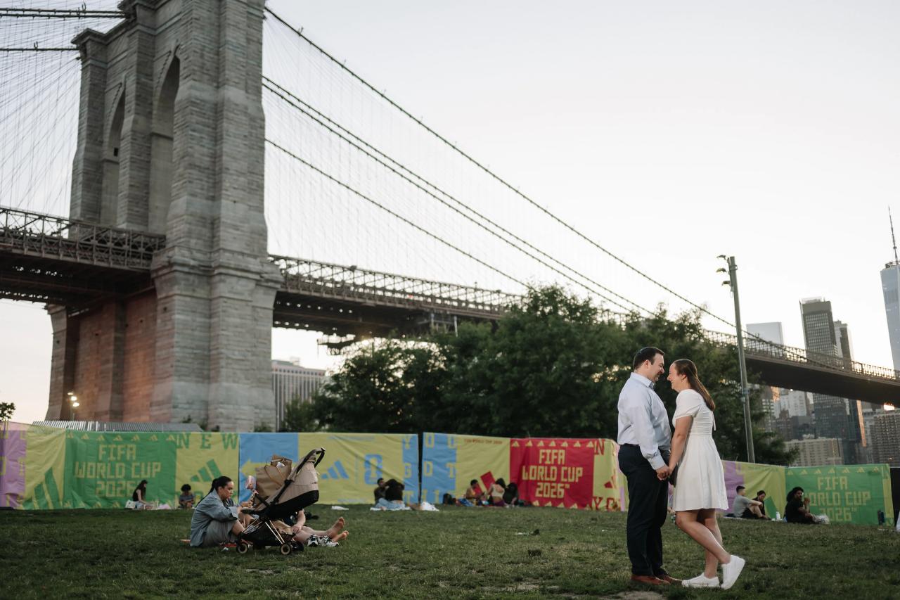 Wide engagement portrait beneath the Brooklyn Bridge