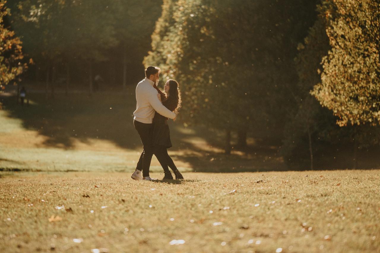 Wide portrait of a couple embracing among golden autumn trees