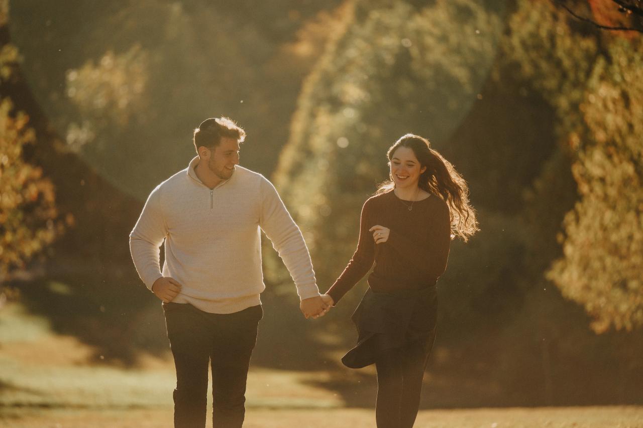 Couple running hand in hand and smiling during their engagement shoot