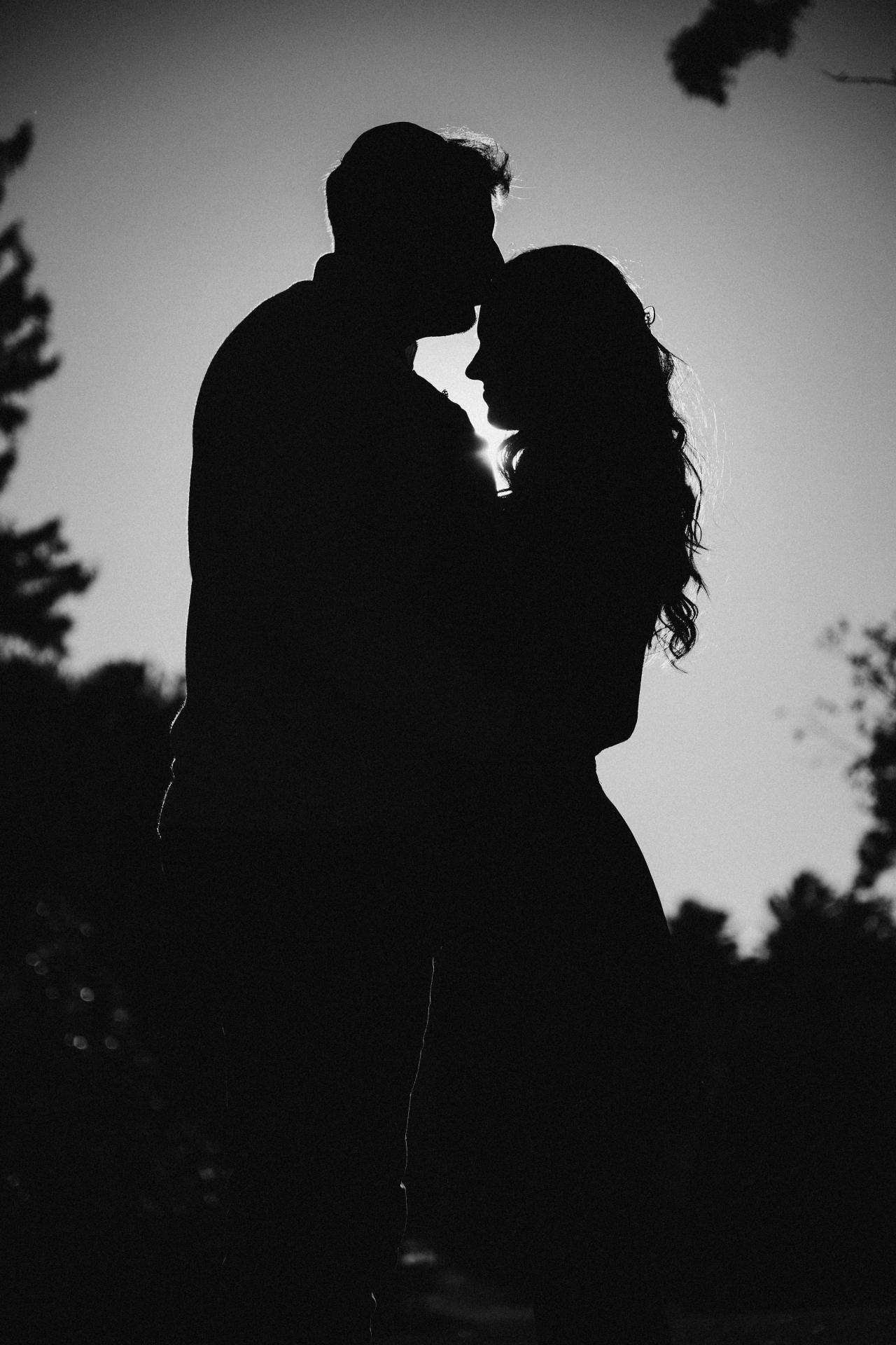 Black-and-white silhouette of a couple kissing outdoors