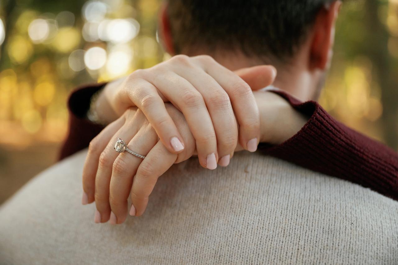 Engagement ring on a hand resting on a partner’s shoulder