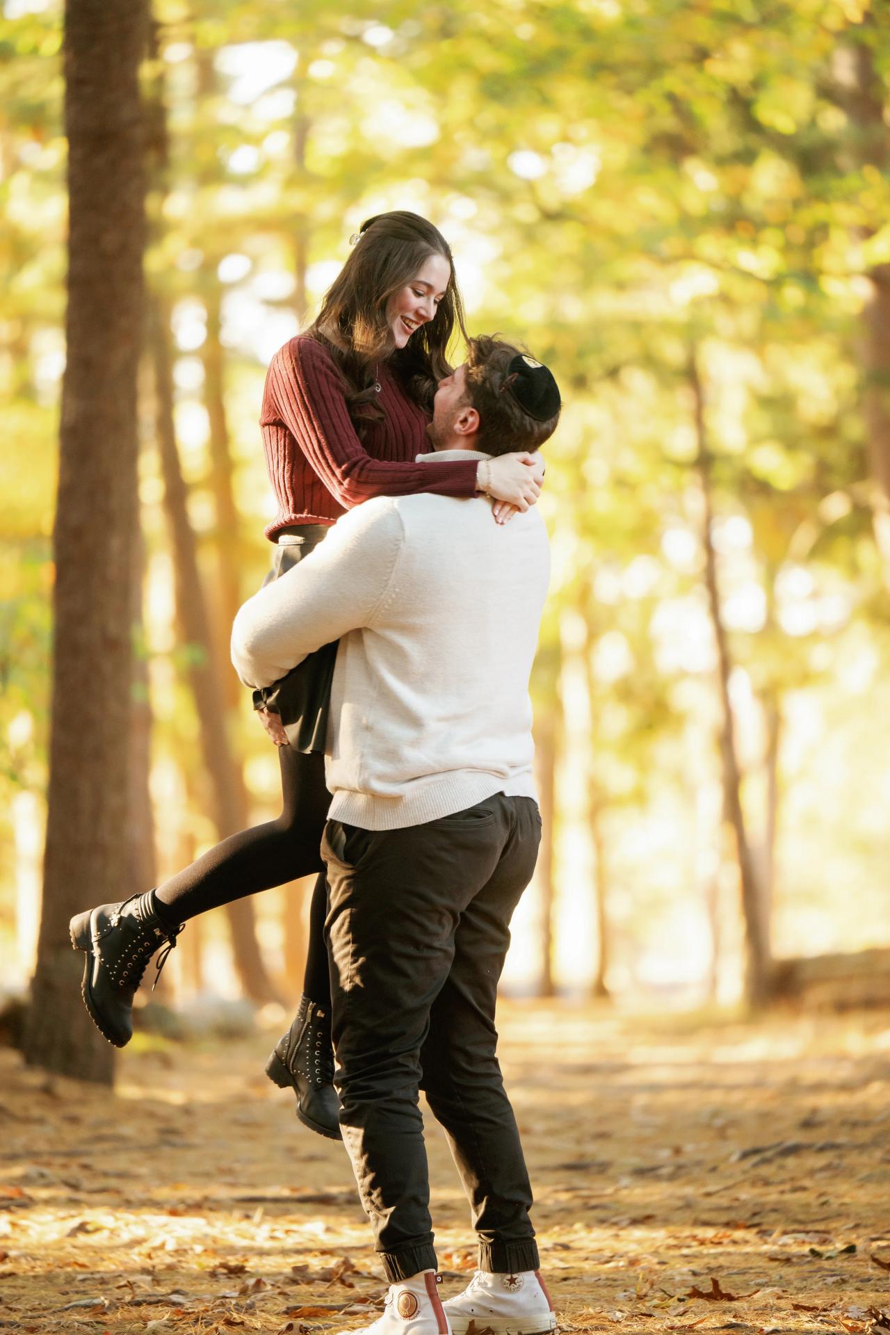 Man lifting his partner during a playful woodland engagement portrait