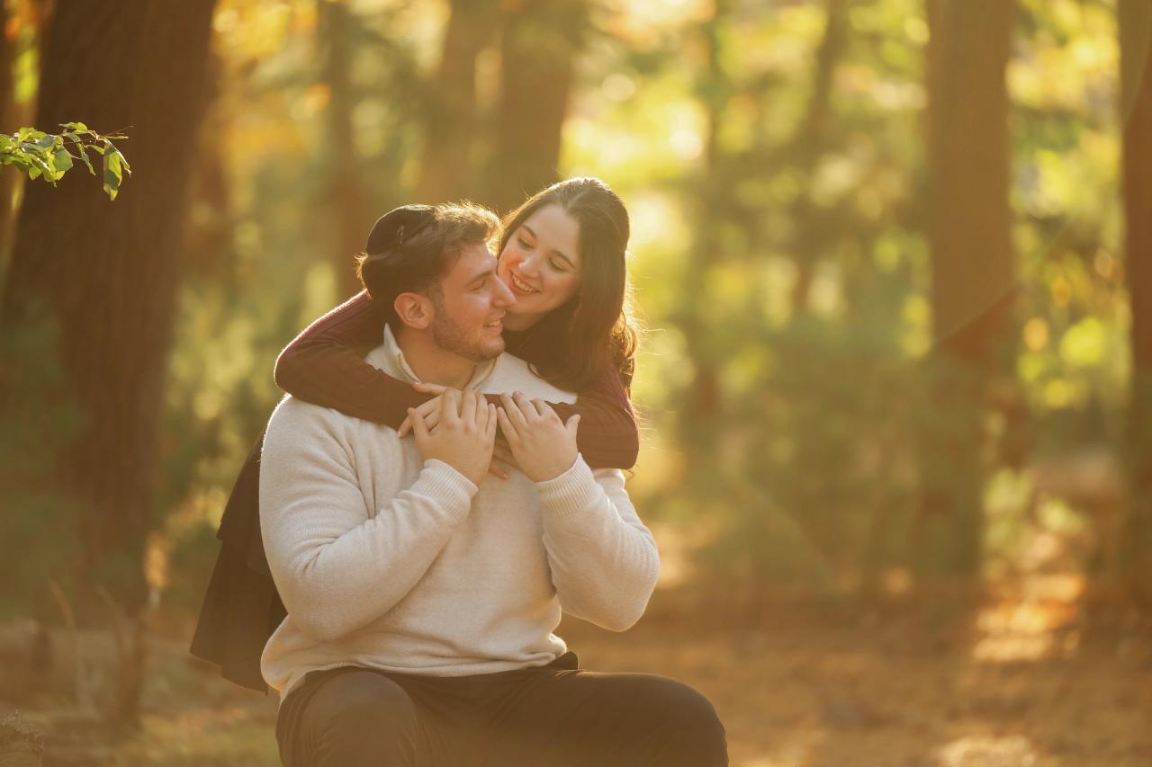 Woman smiling while her partner kisses her during a piggyback portrait