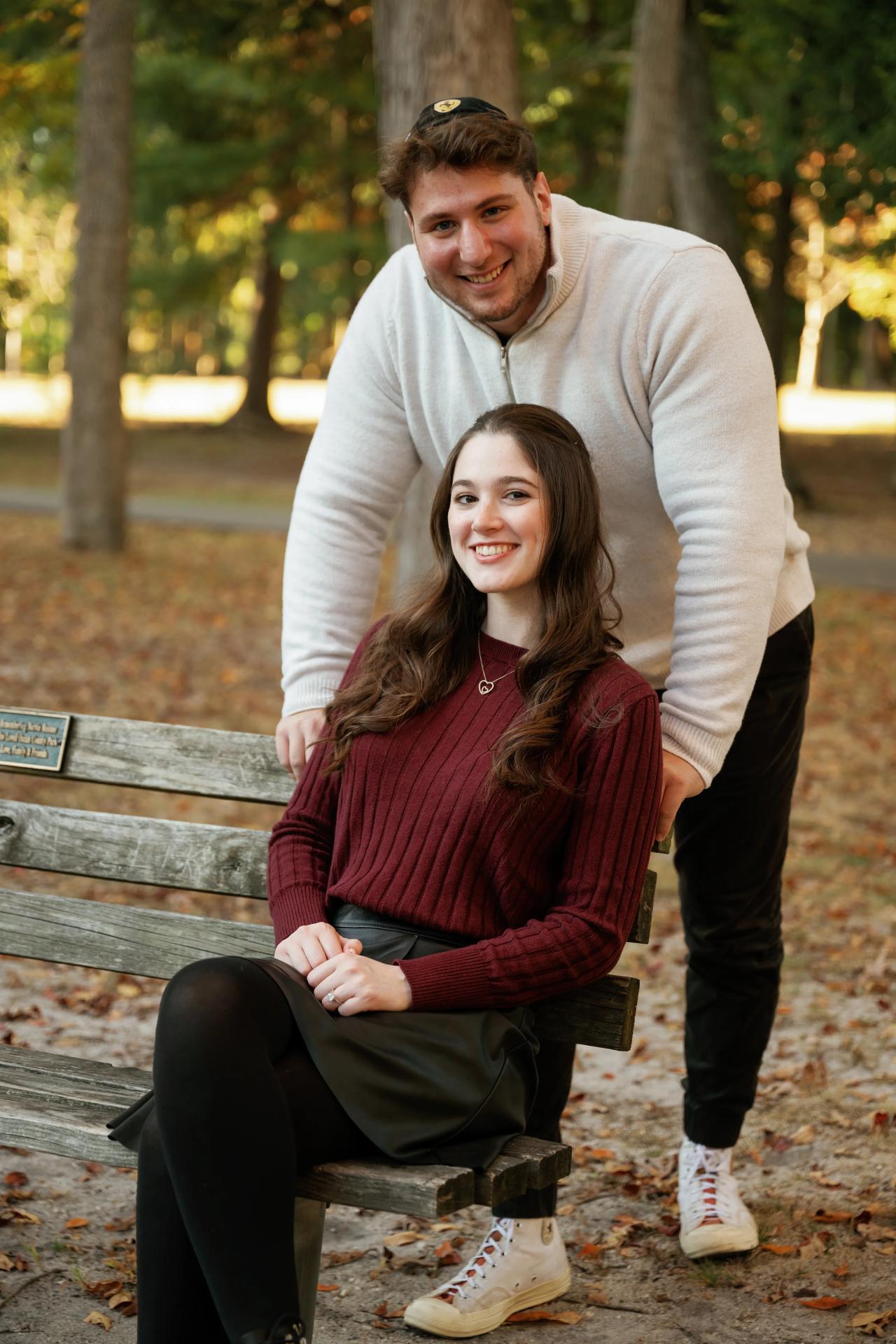 Couple smiling together beside a wooden park bench