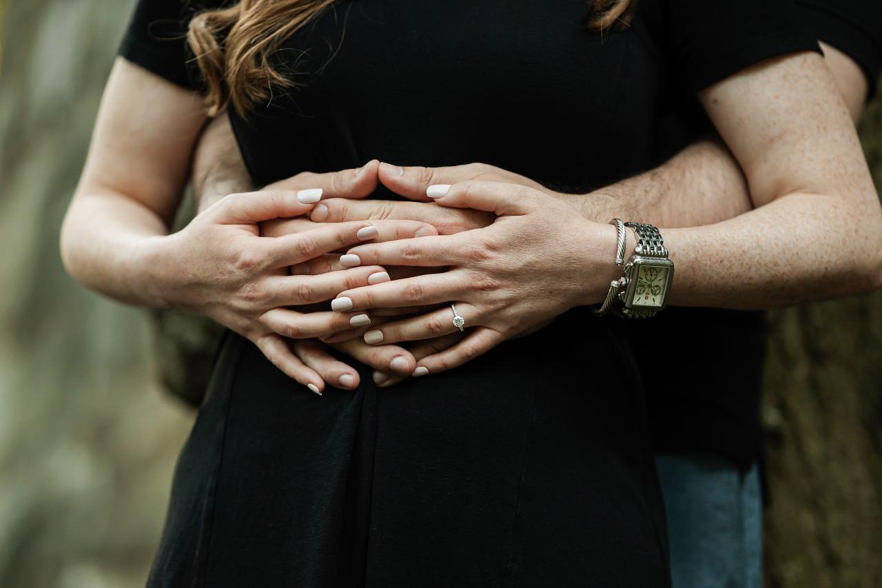 Close-up of a couple holding hands with an engagement ring visible
