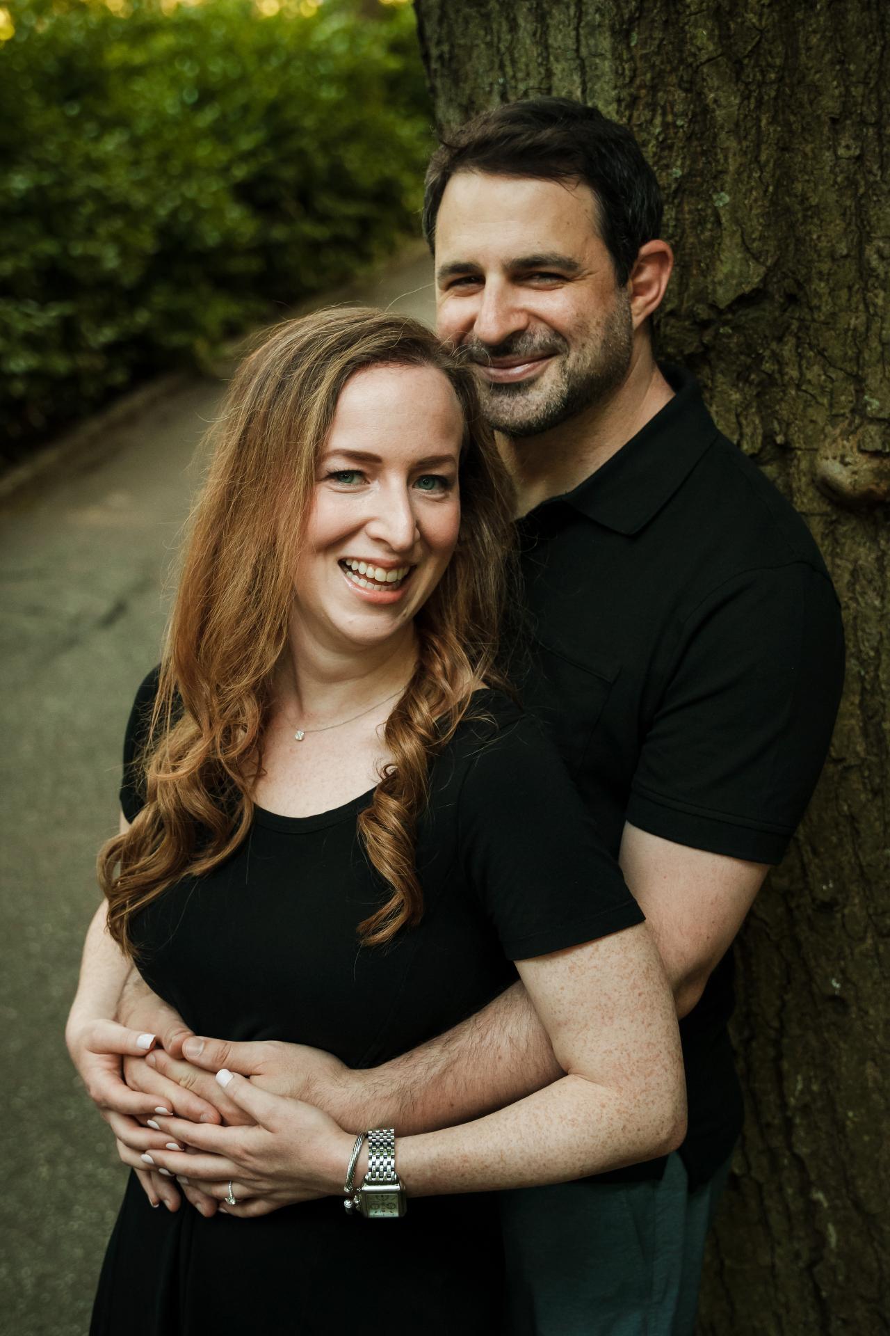 Couple smiling together beneath green summer foliage