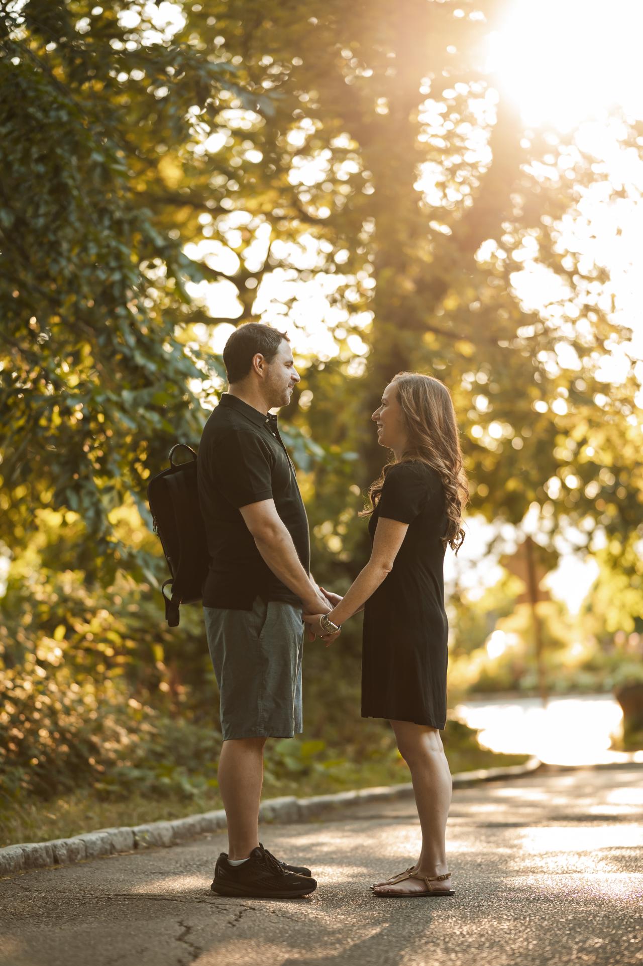 Couple holding hands in warm sunlight beneath the trees