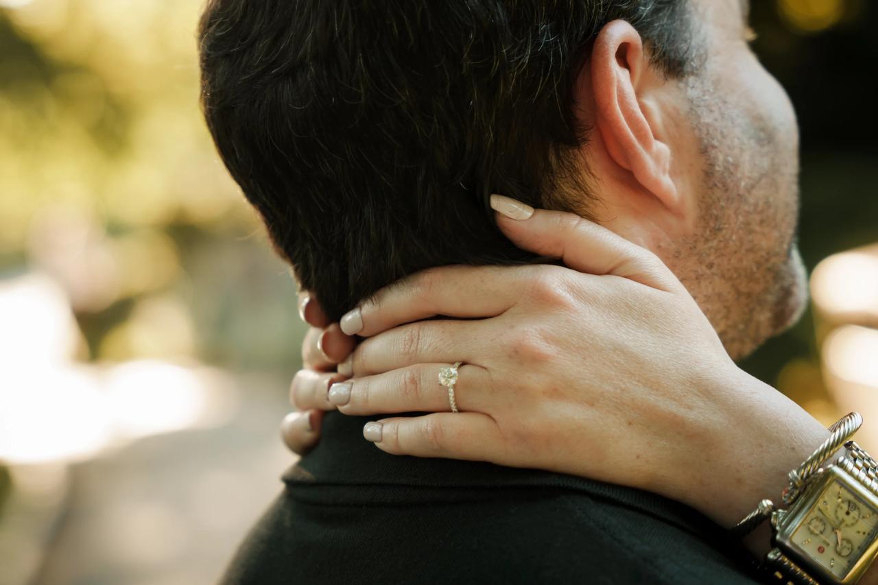 Engagement ring on a hand resting around a partner’s neck
