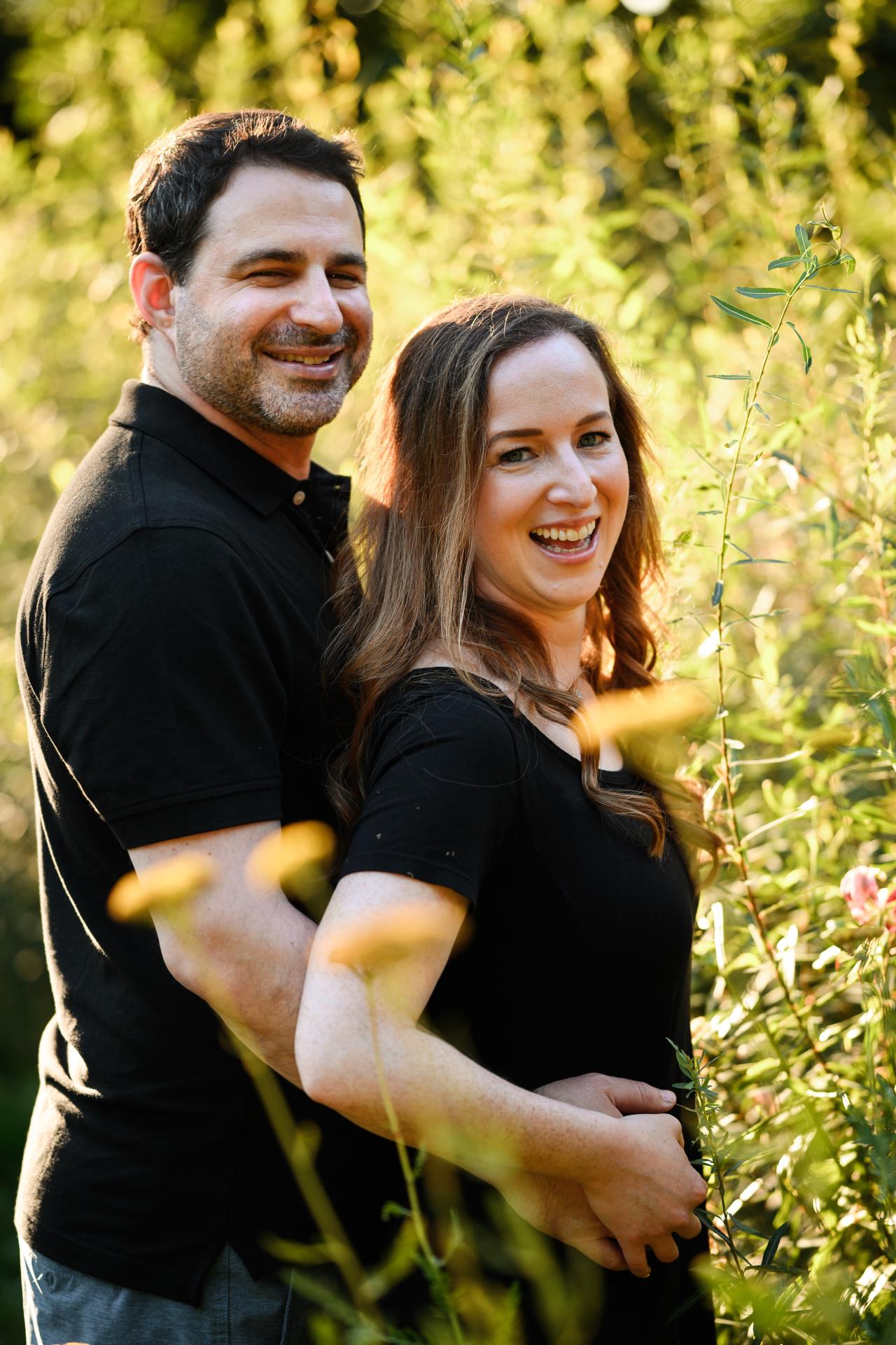 Couple smiling together among tall grasses in evening light