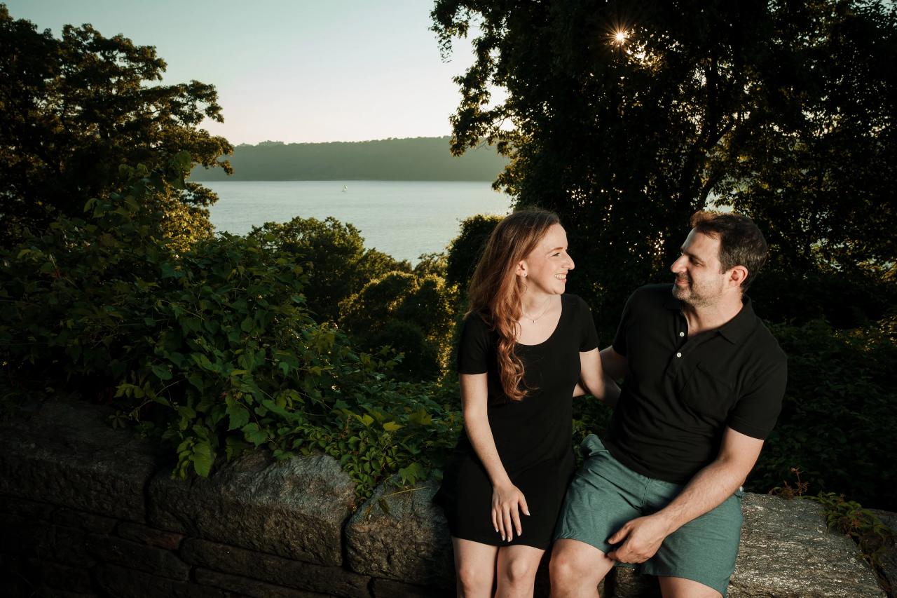 Couple seated together on a stone wall with water behind them