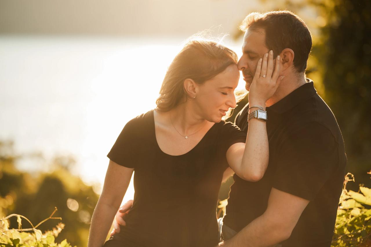 Woman resting her hand on her partner’s face beside the water