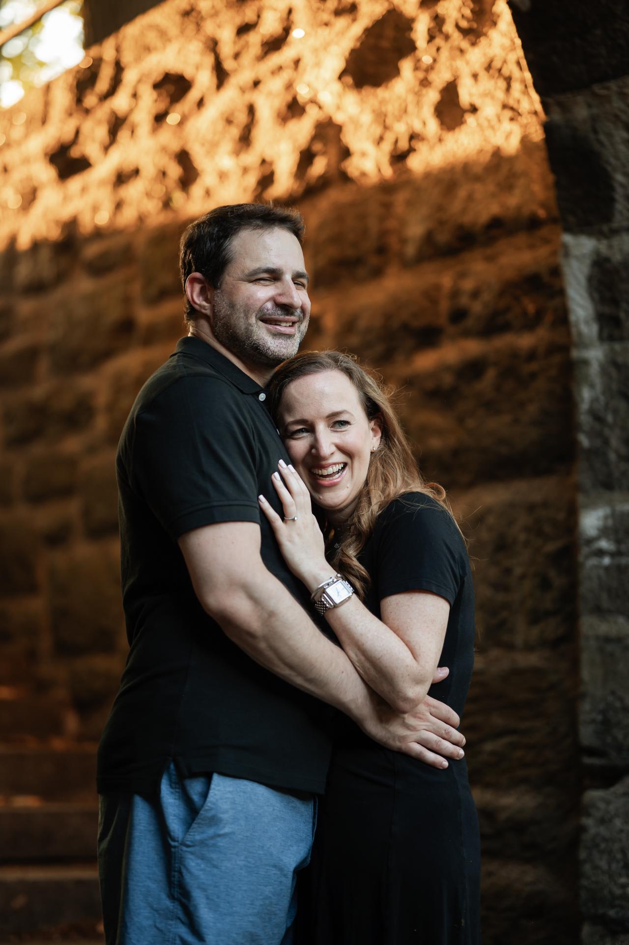 Couple sharing an embrace beside a warmly lit stone archway