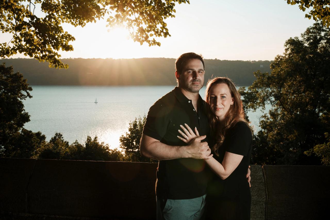 Couple standing together at a leafy overlook above the water