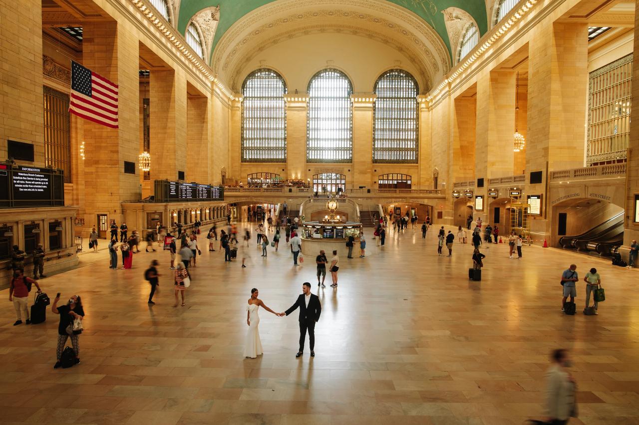 Wide view of an engaged couple holding hands in Grand Central Terminal