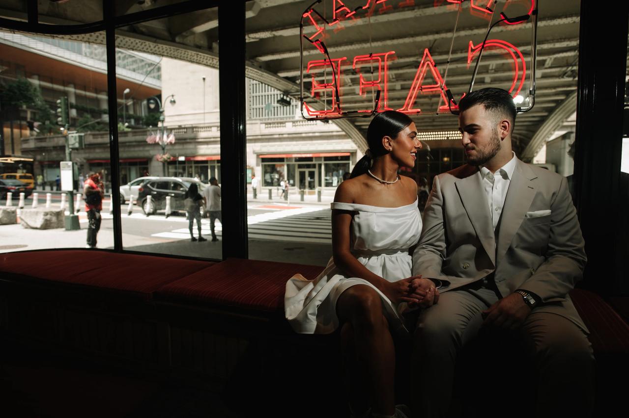 Couple seated together beside a cafe window during their engagement shoot