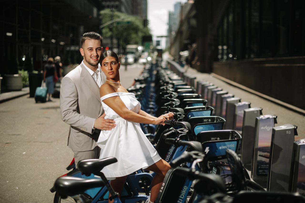 Couple smiling together beside a row of blue city bicycles
