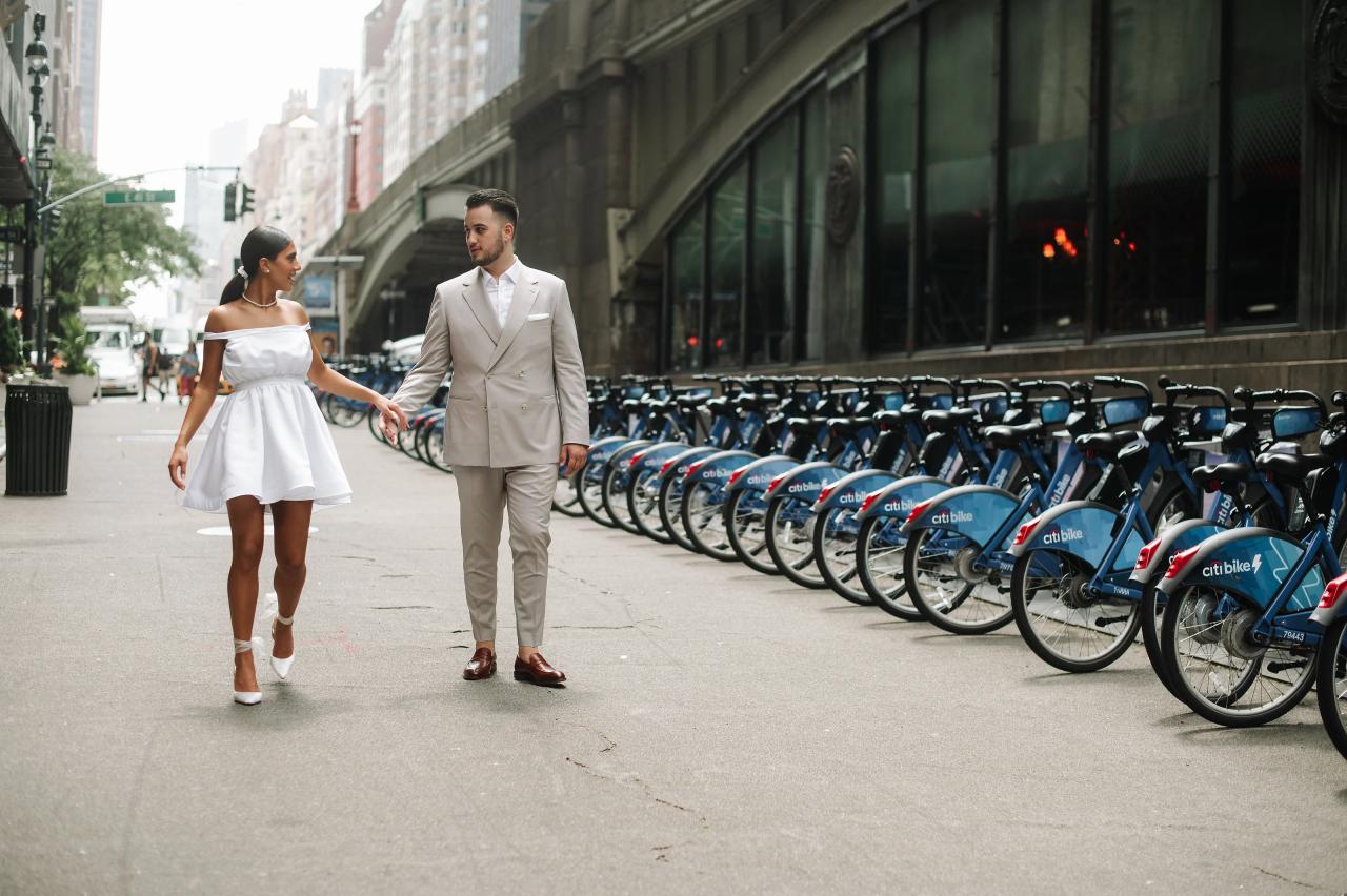 Engaged couple holding hands during a relaxed walk along a city sidewalk
