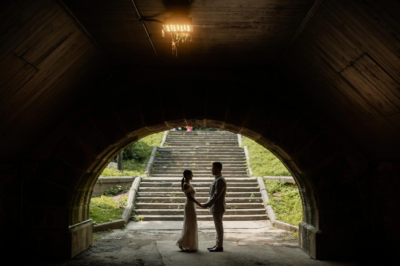 Silhouette of a couple holding hands beneath a Central Park archway