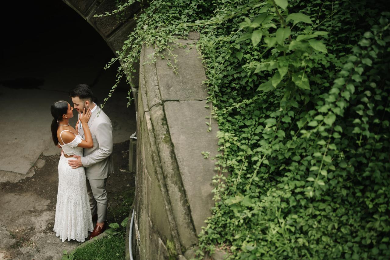 Engagement portrait of a couple framed by green ivy and stonework