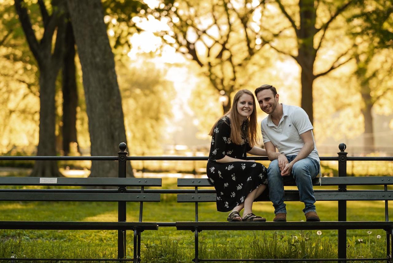 Couple sharing a sunlit park bench during their spring engagement session