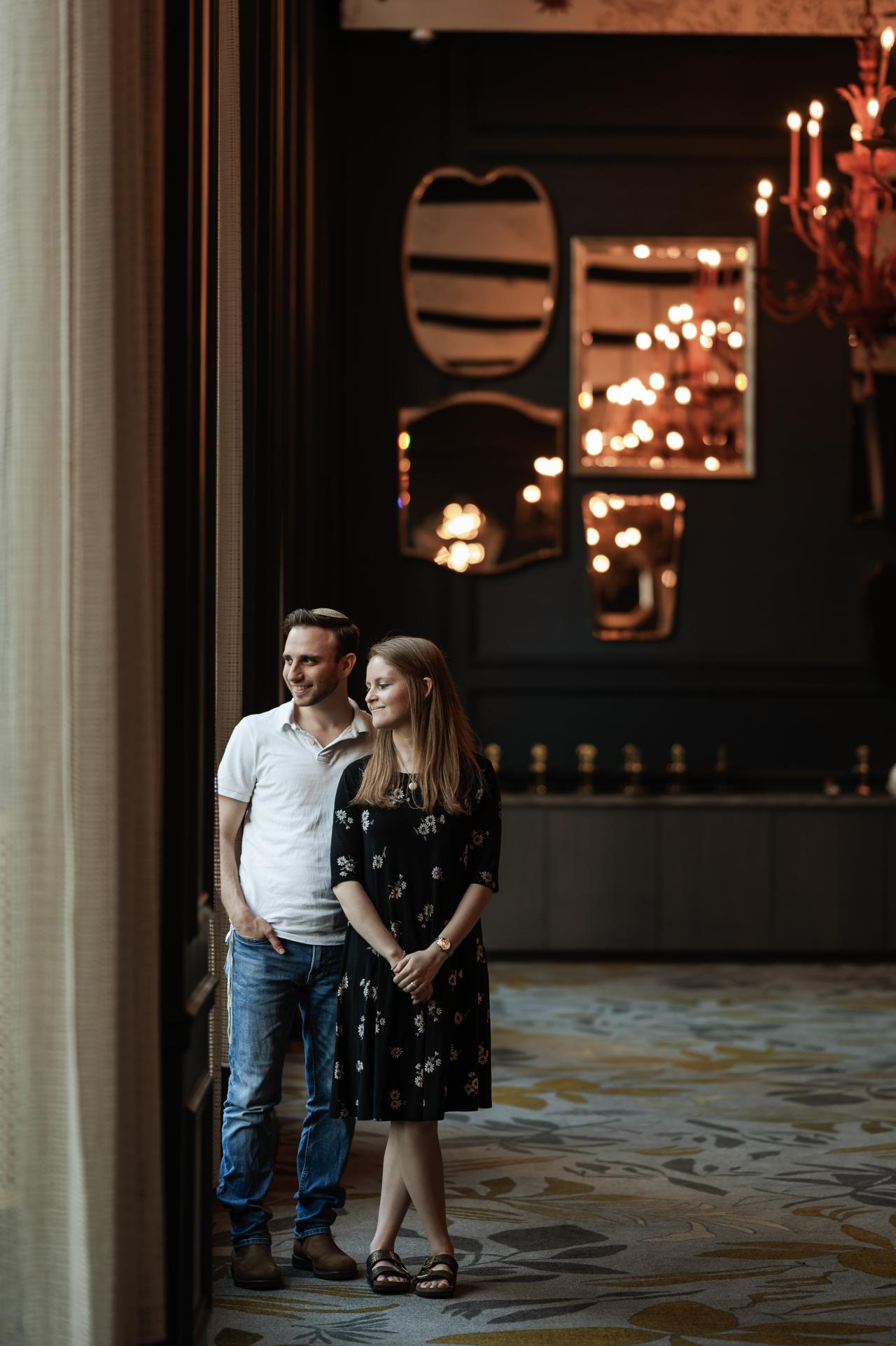 Full-length engagement portrait beside a tall window