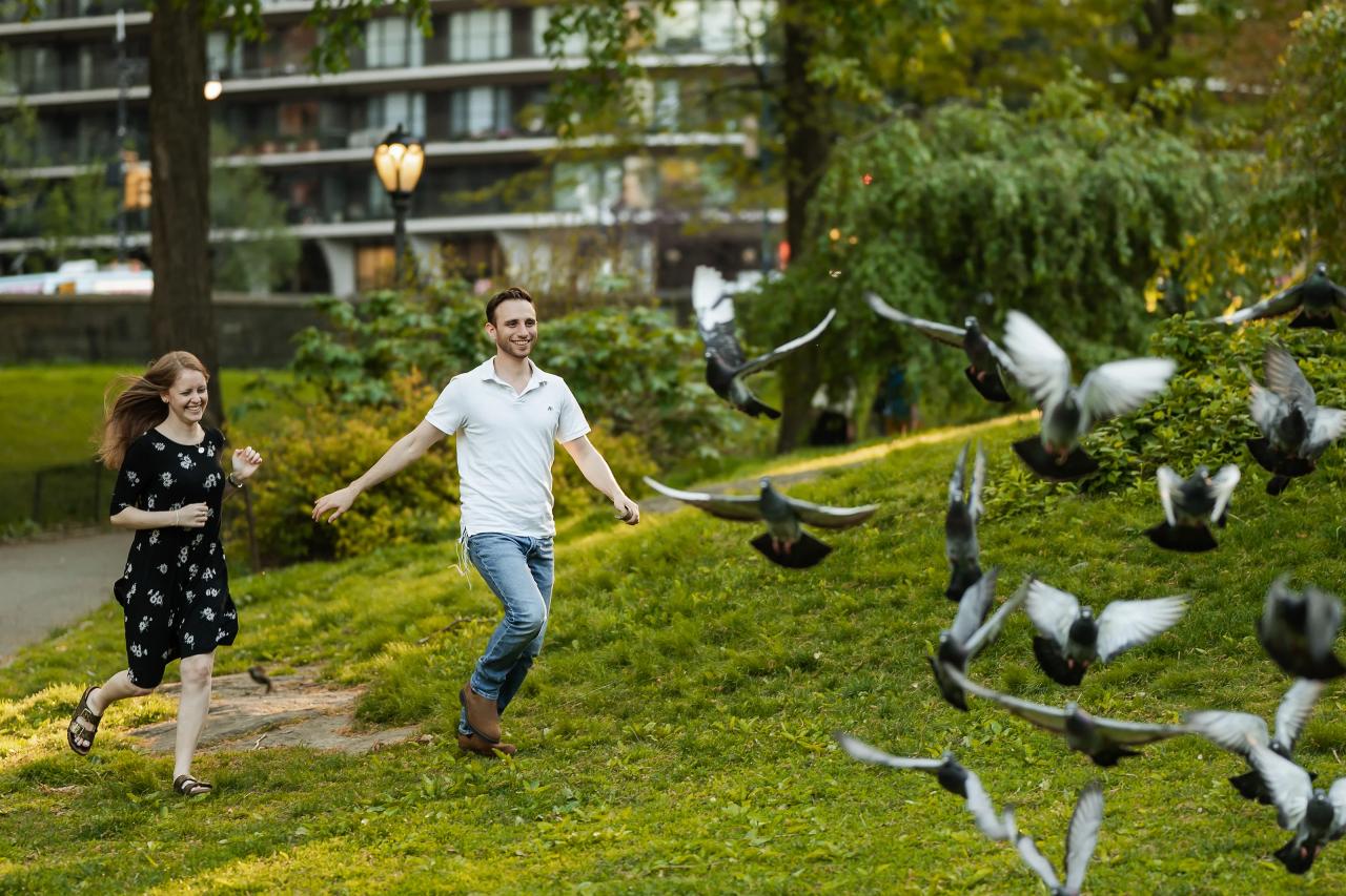 Couple running hand in hand as pigeons take flight