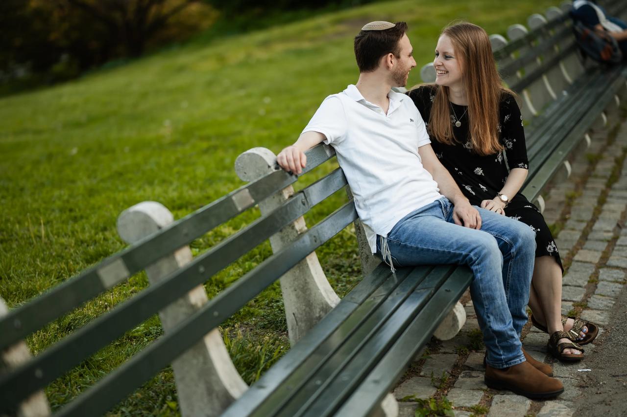 Couple smiling at each other on a long park bench