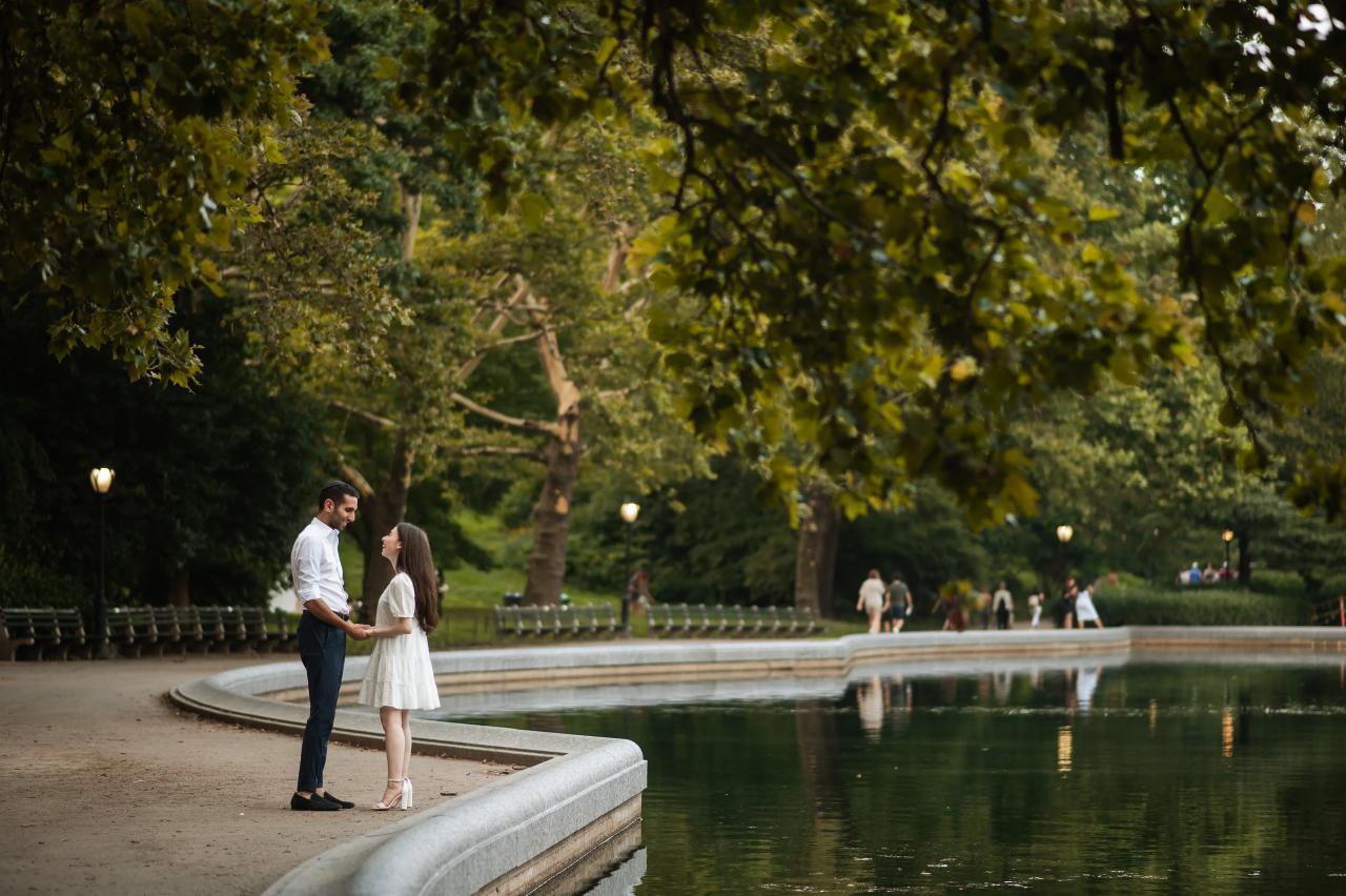 Wide engagement portrait beside the water in Central Park