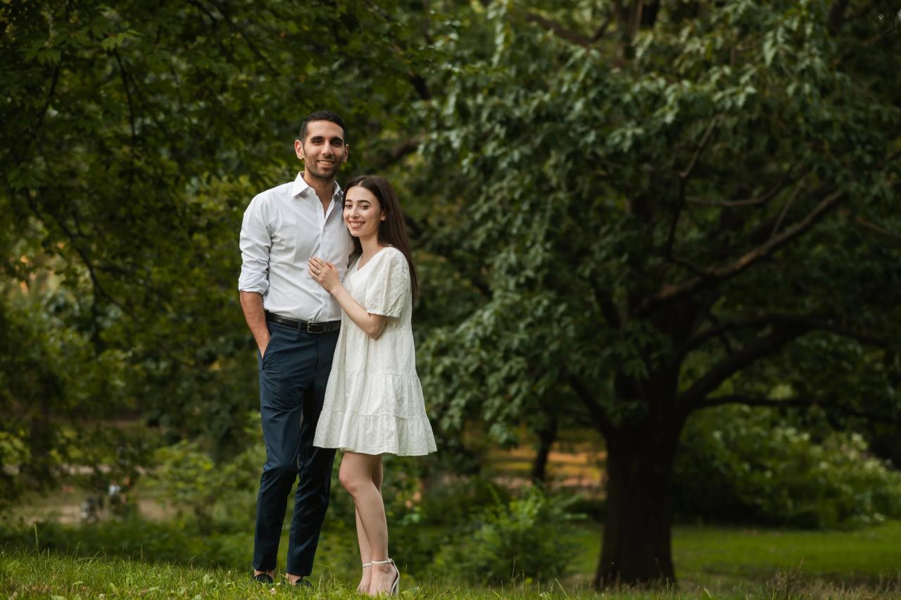 Couple standing together beneath leafy trees in Central Park