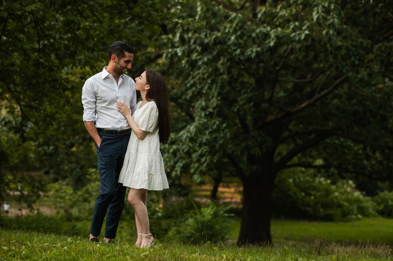 Couple sharing a kiss on a shaded lawn