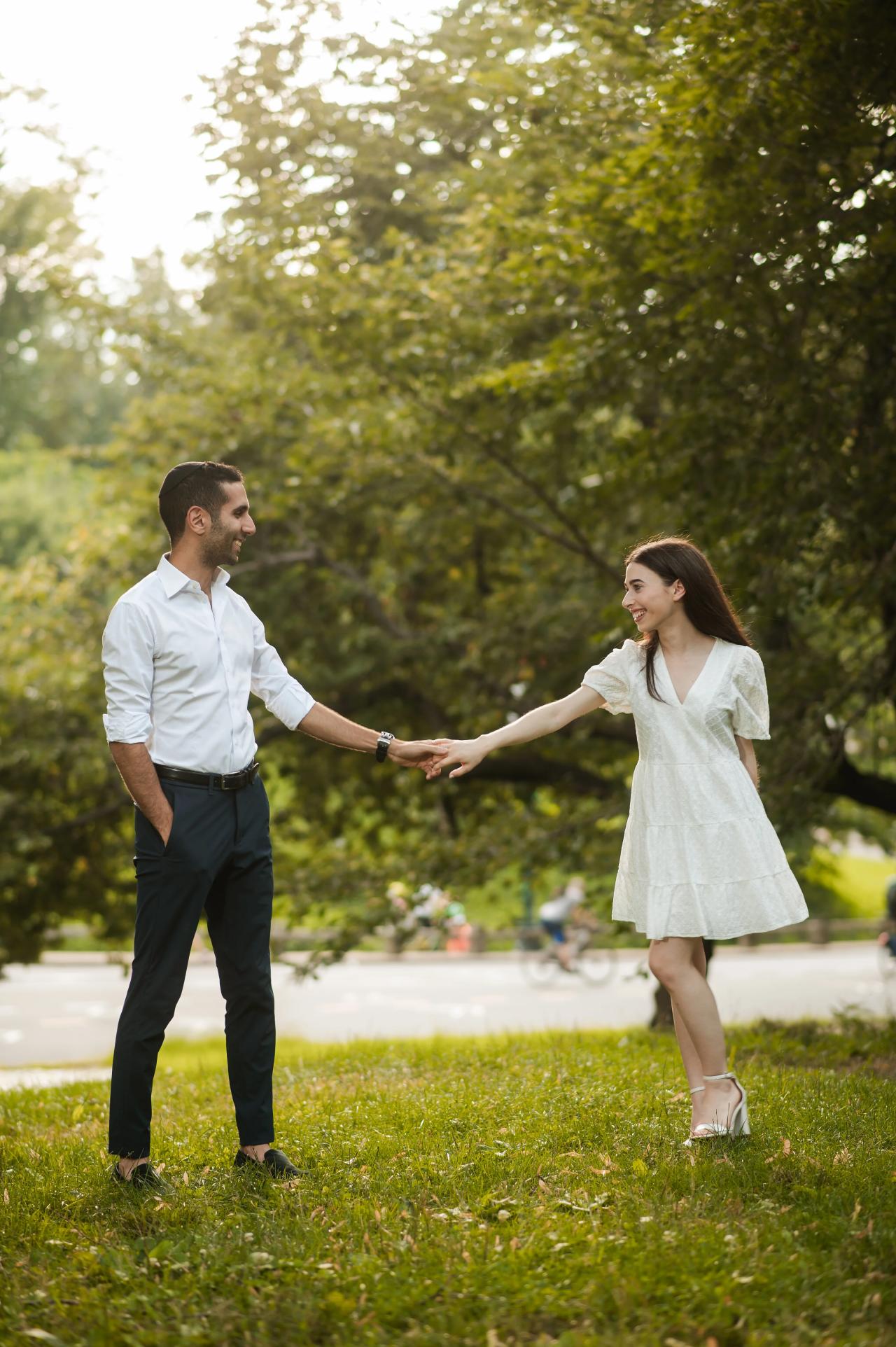 Couple holding hands across a sunlit lawn