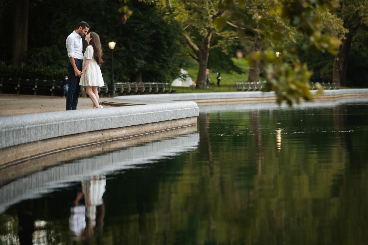 Couple reflected in the water beside a curved stone edge