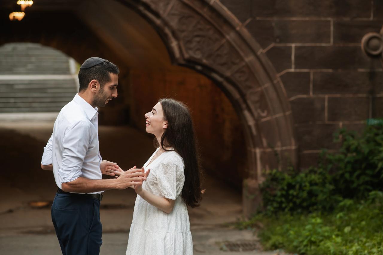 Couple facing each other beside a carved stone arch