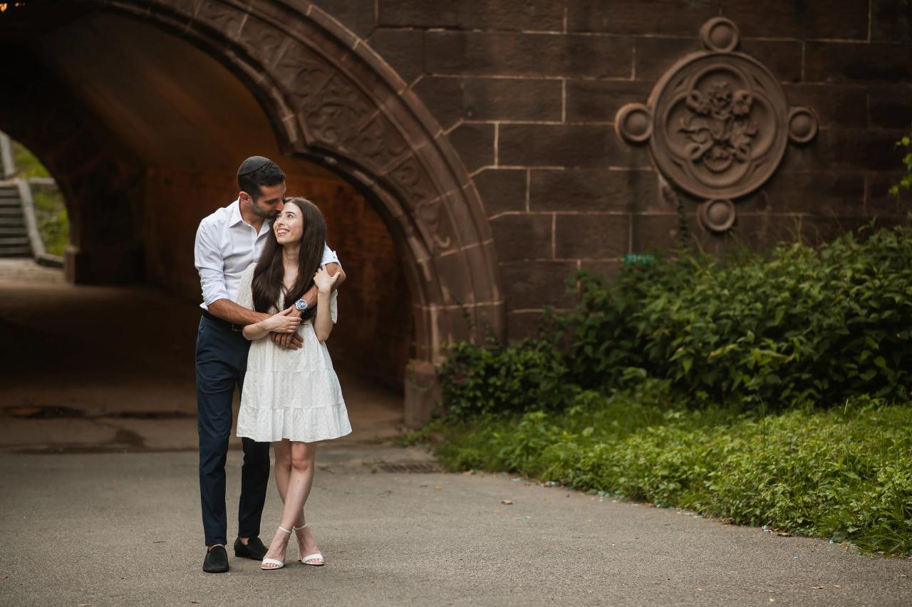 Couple standing together beneath an ornate stone arch