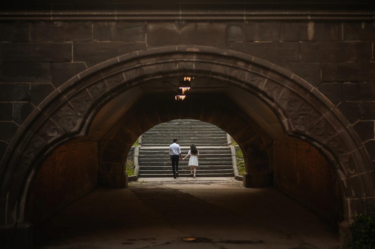 Couple framed by a dark archway and bright stone stairs