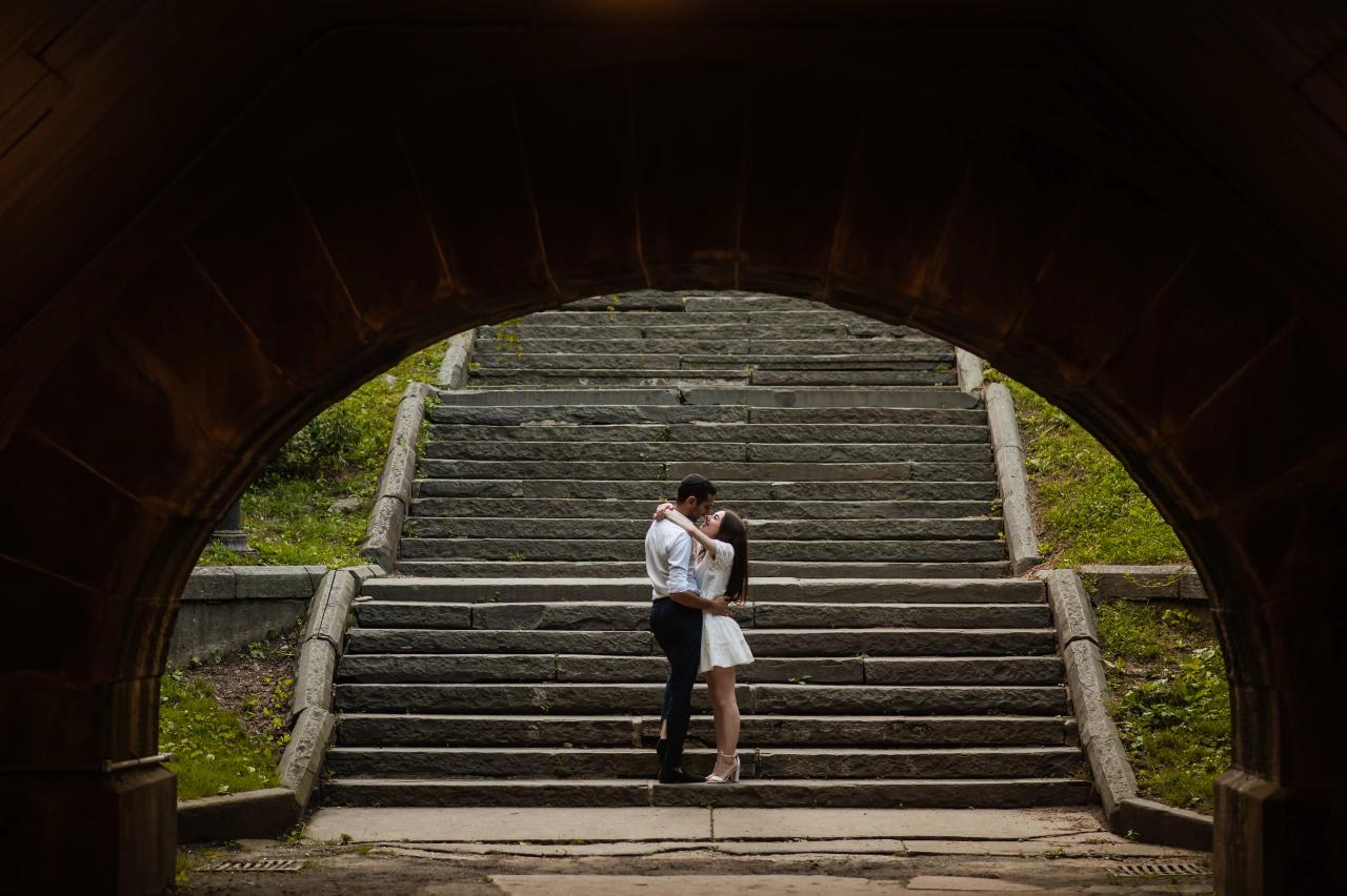 Couple embracing on steps beneath a stone arch