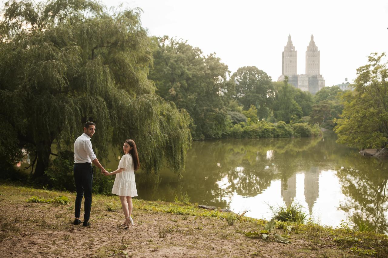Couple holding hands beside the lake and willow trees