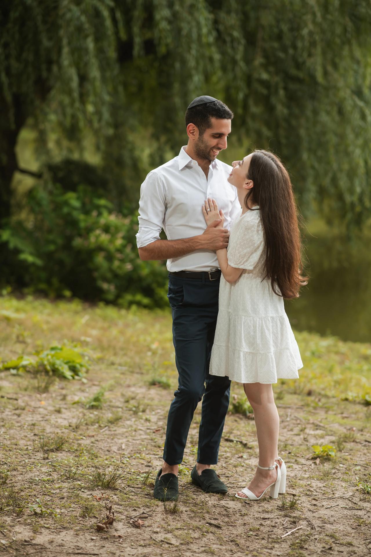 Couple sharing a kiss beneath willow branches