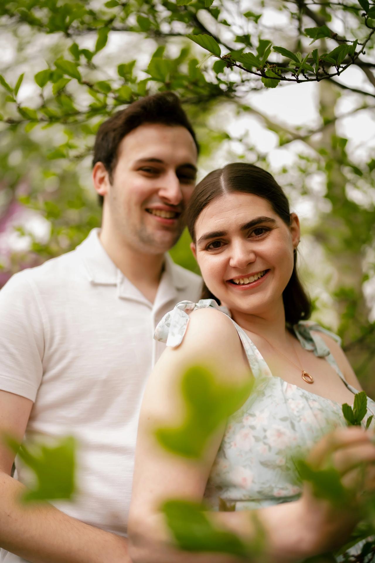 Couple smiling together beneath leafy branches
