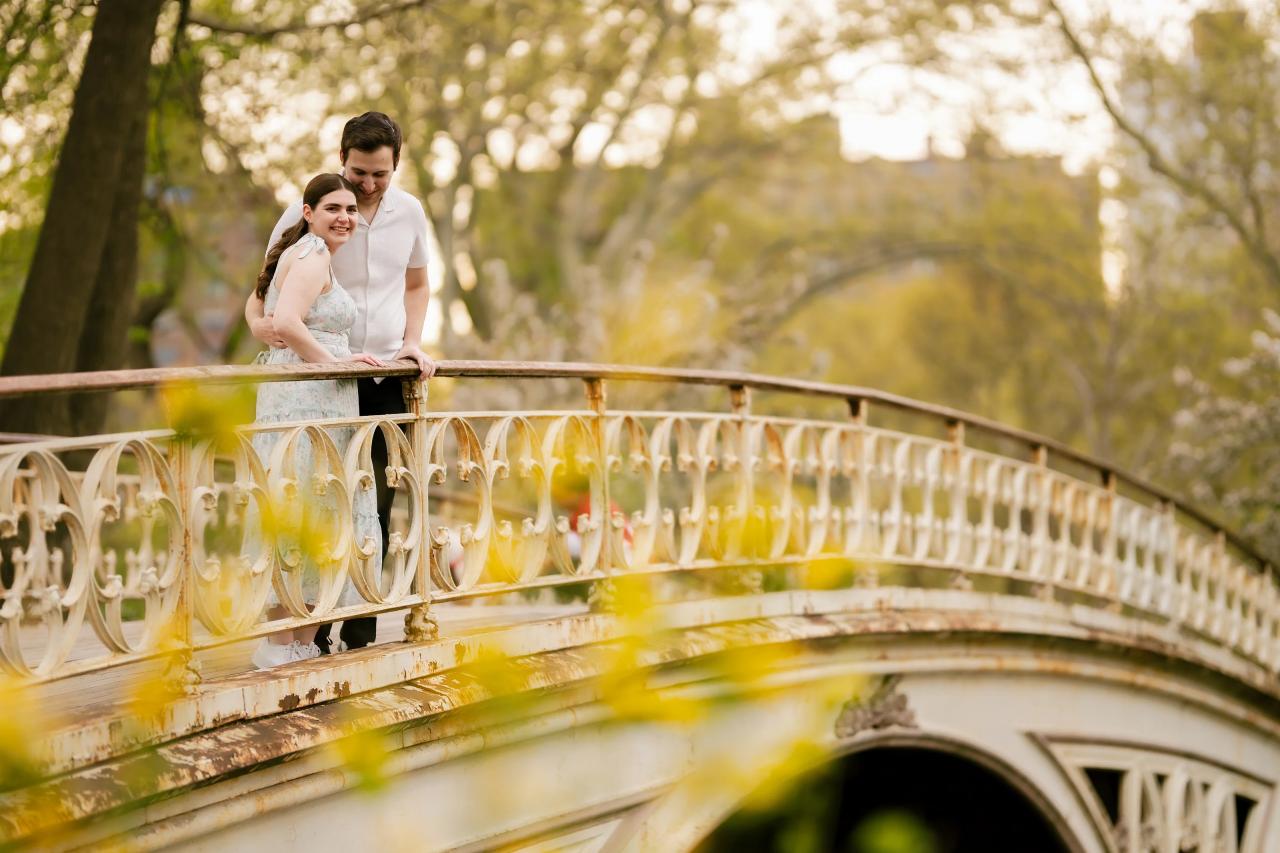 Couple framed by the decorative railing of a park bridge