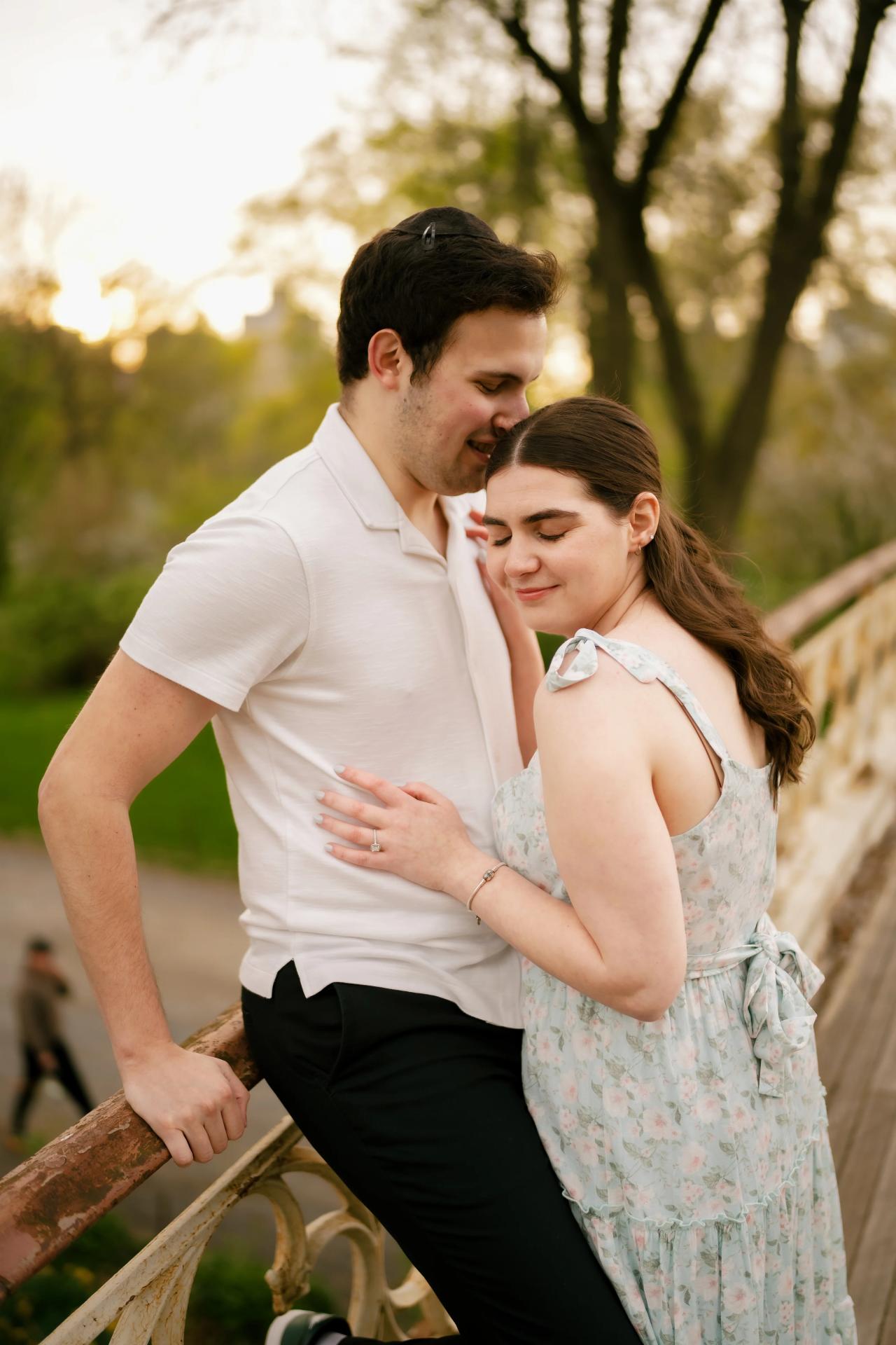 Couple embracing beside a pale decorative bridge railing