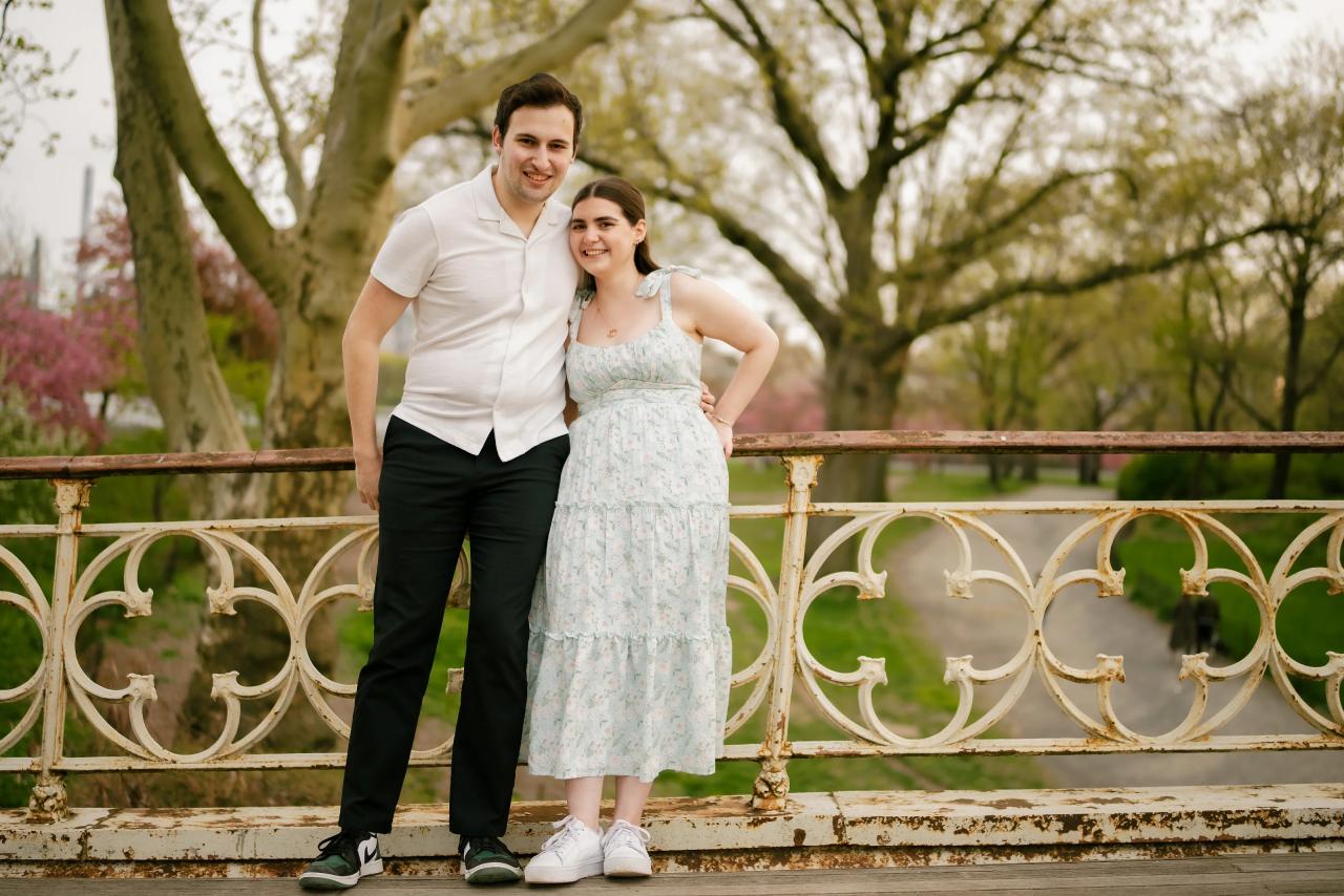 Full-length couple portrait on a park footbridge