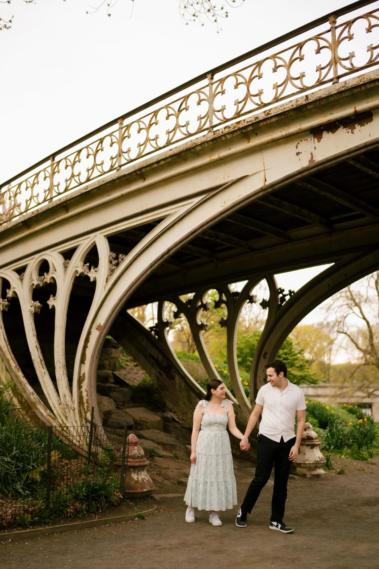 Couple walking hand in hand beneath a bridge