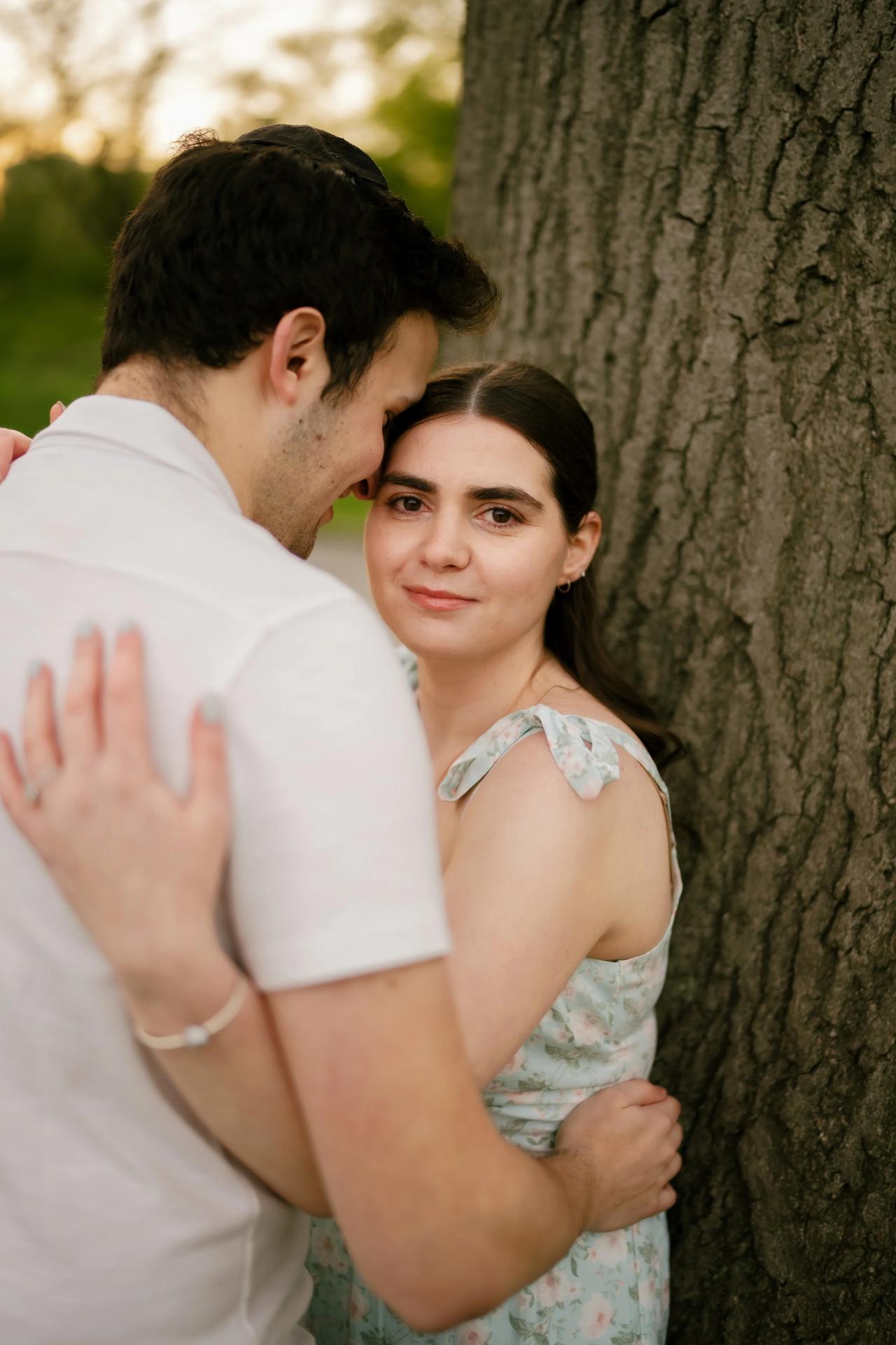 Couple embracing beside a broad tree trunk