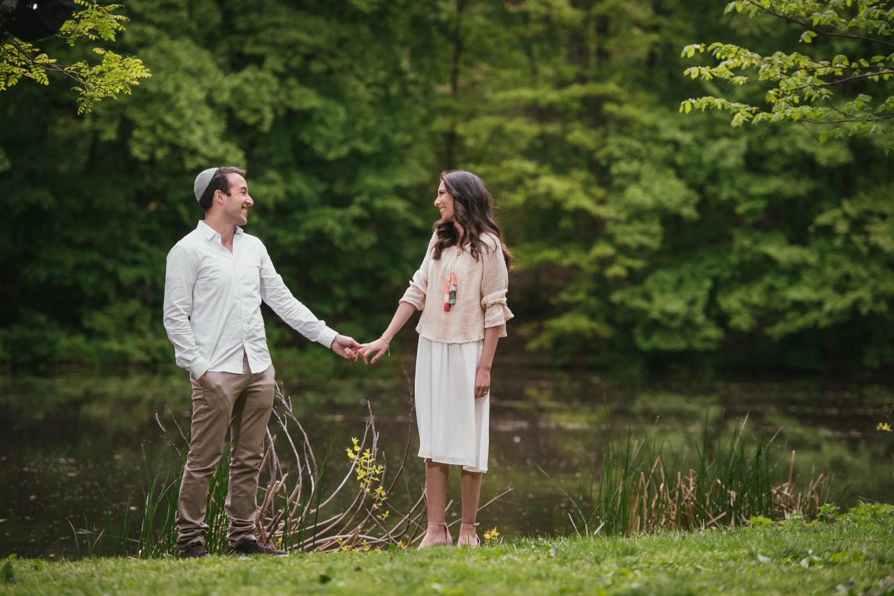 Couple holding hands beside a wooded pond